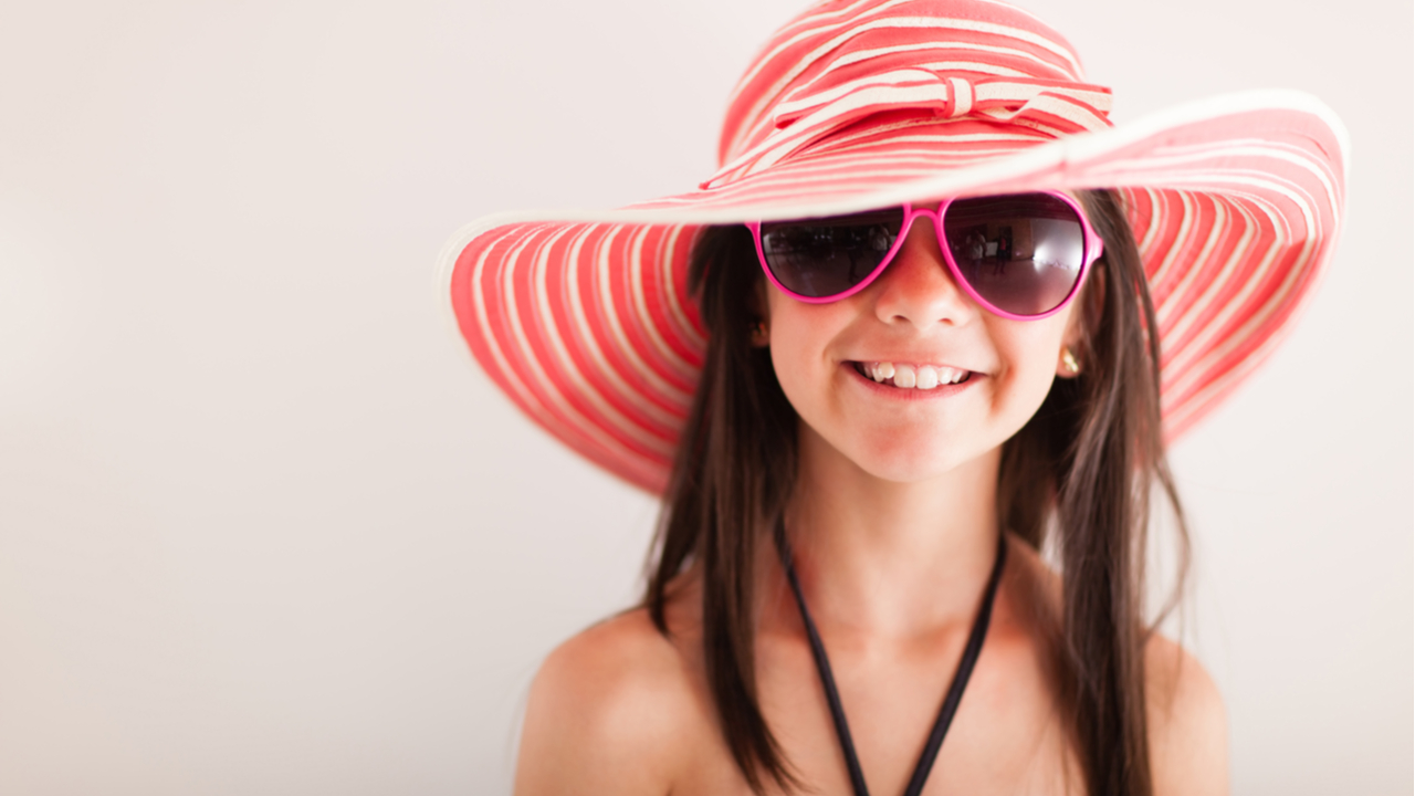 niña alegre con sombrero de playa 