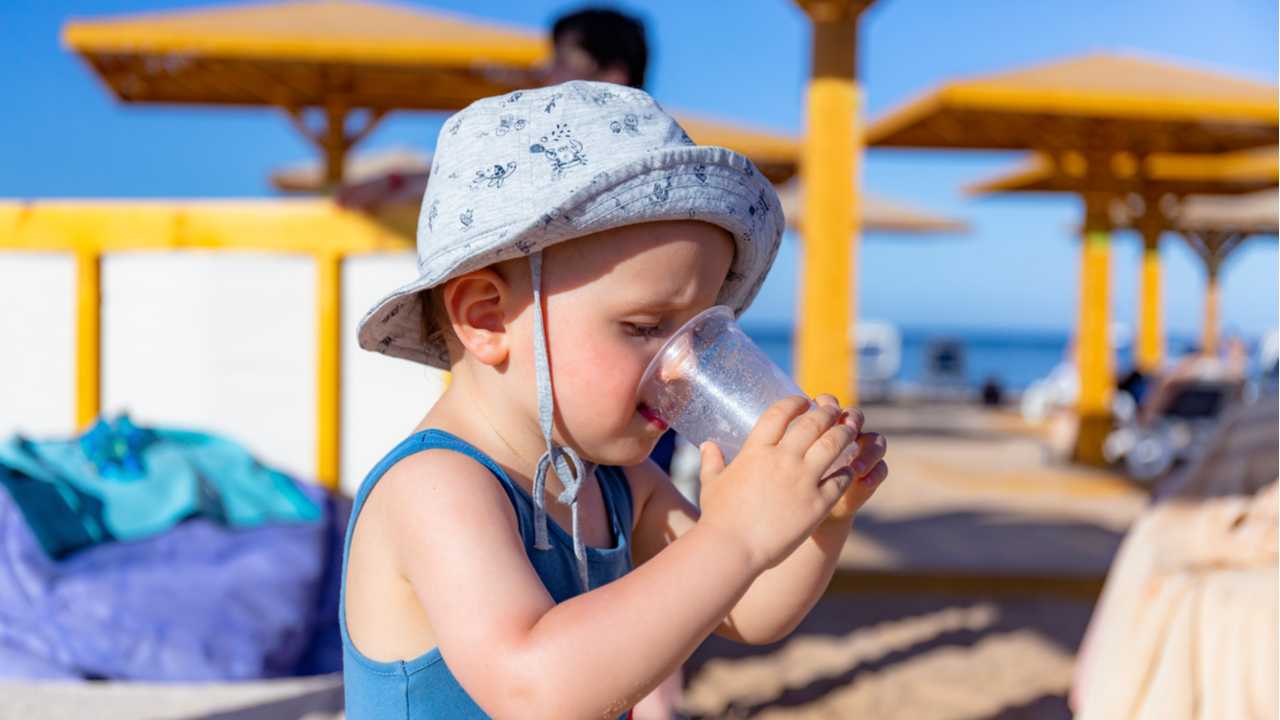 bebe tomando agua en la playa 