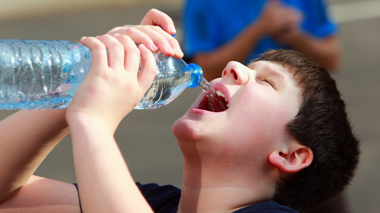 niño tomando botella de agua