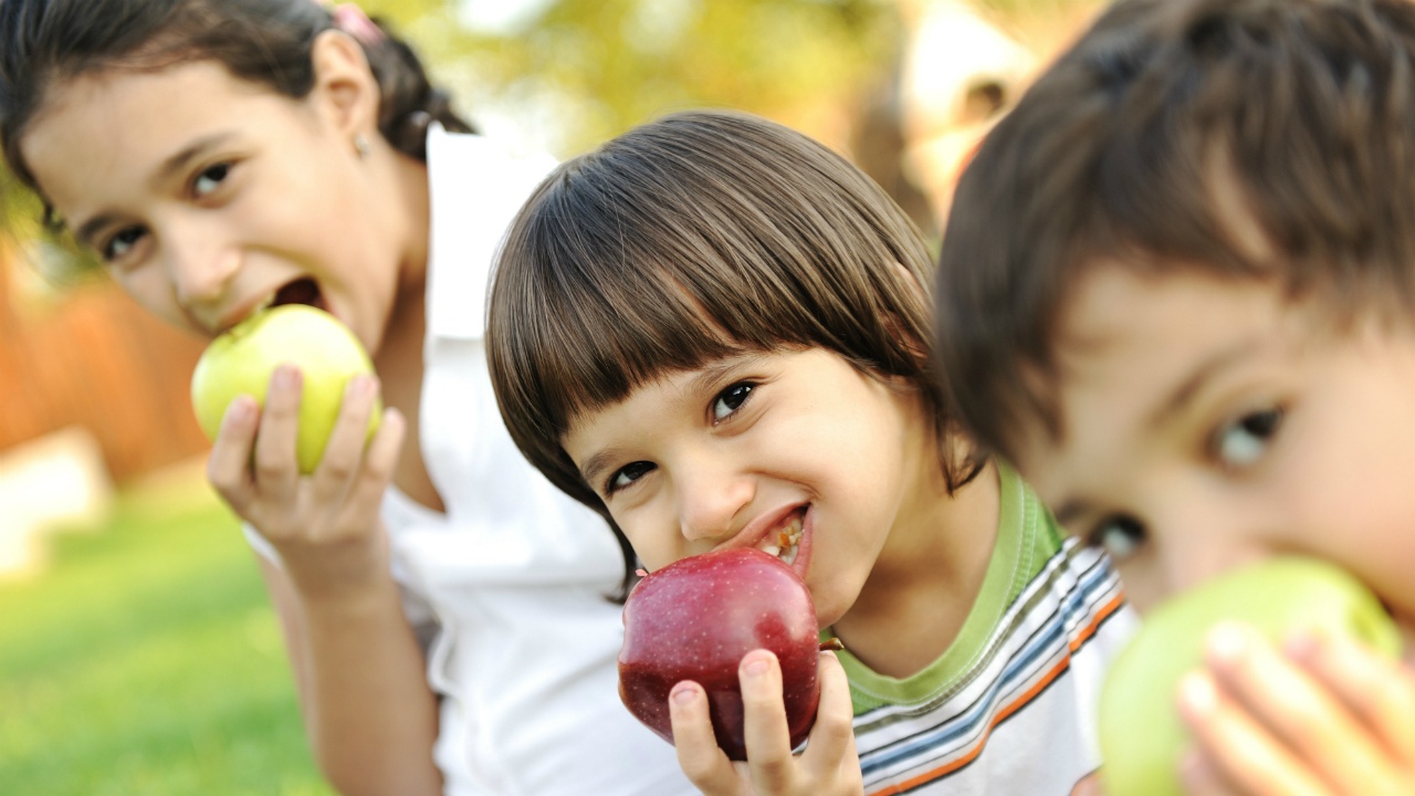 tres niños comiendo manzanas