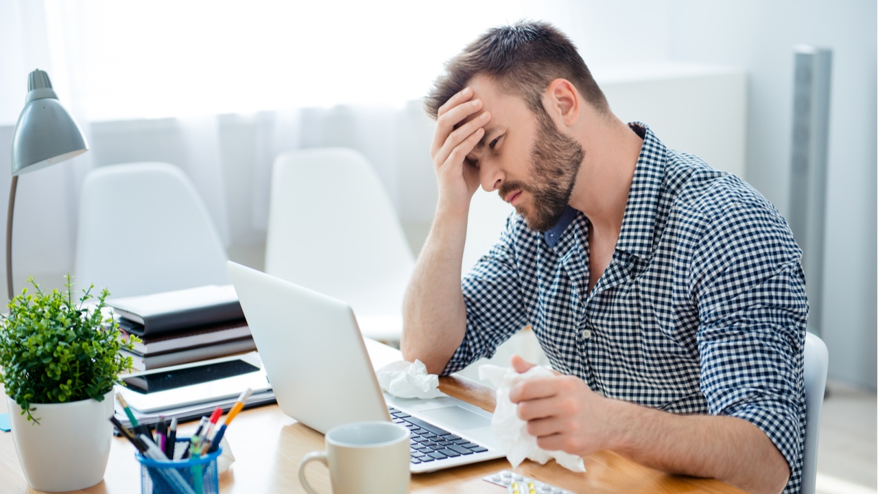 hombre en laptop con dolor de cabeza